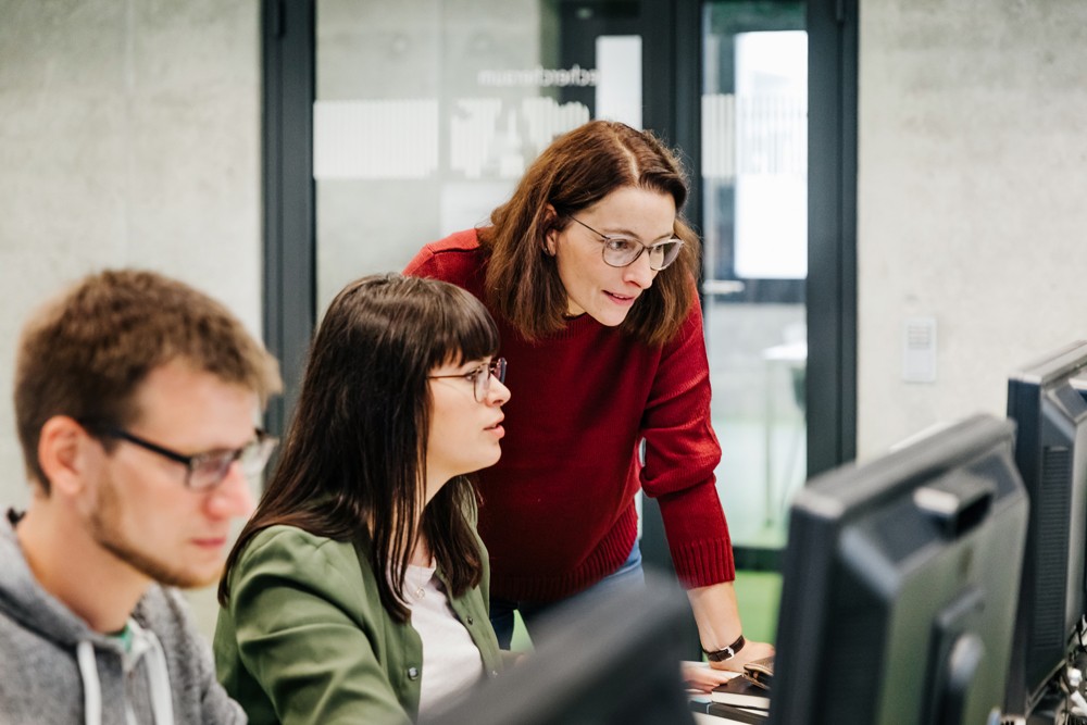 Three employees looking at computer