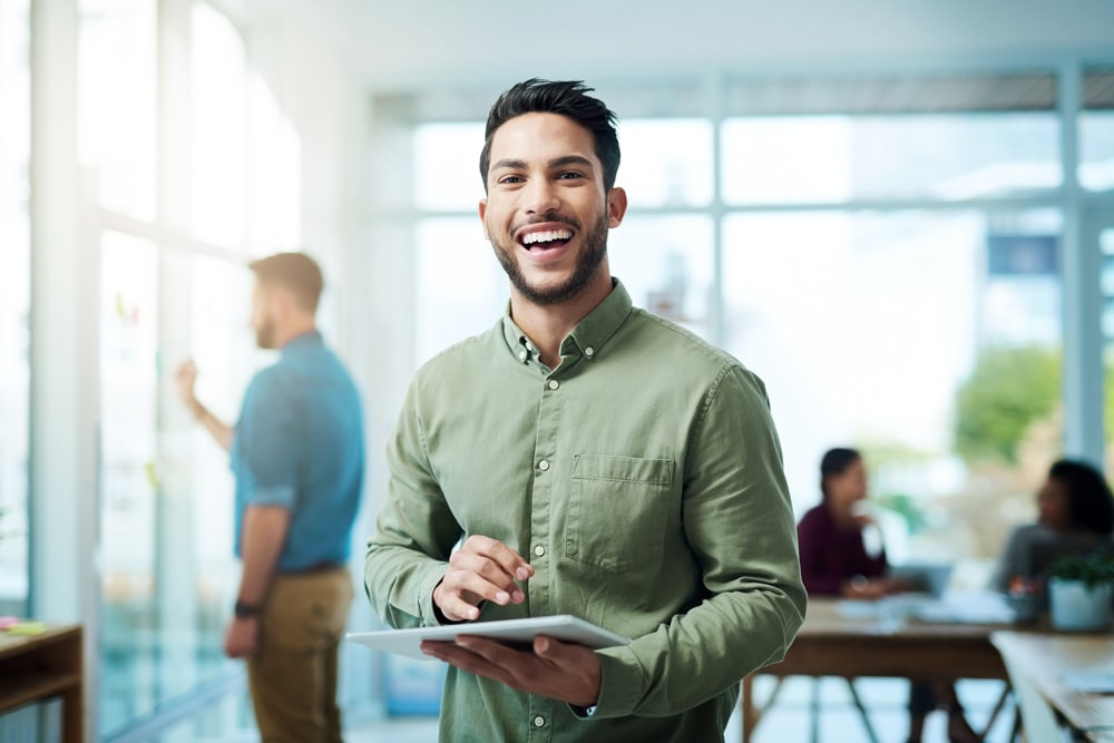 Man in green with tablet smiling